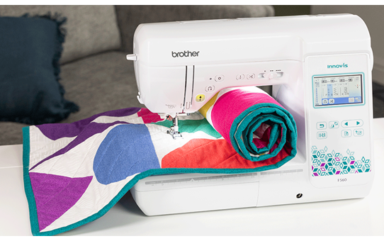 Brother Innov-is F560 sewing machine with colourful quilt on table