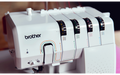 Close-up of the Brother Airflow 3000 overlocker showing colour-coded threading guides and tension dials