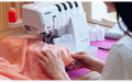 Person overlocking peach fabric on the Brother Airflow 3000 overlocker