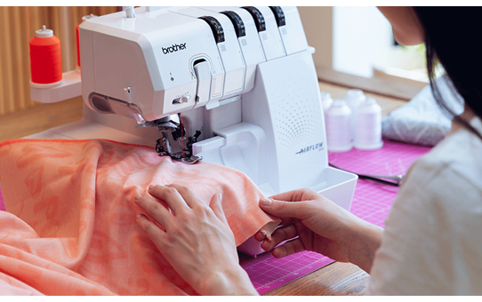 Person overlocking peach fabric on the Brother Airflow 3000 overlocker