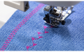 Brother Innov-is F560 stitching a decorative pink pattern on blue denim fabric