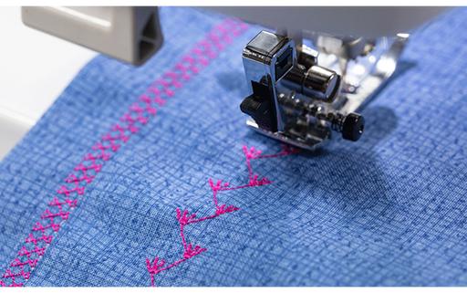 Brother Innov-is F560 stitching a decorative pink pattern on blue denim fabric