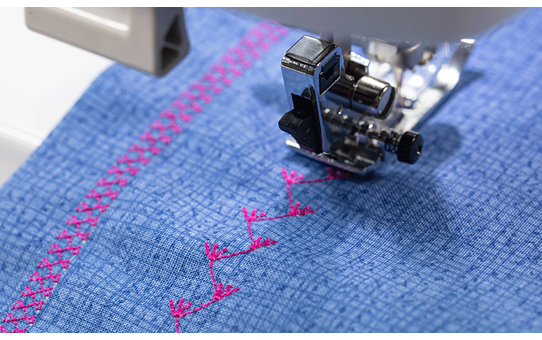 Brother Innov-is F560 stitching a decorative pink pattern on blue denim fabric