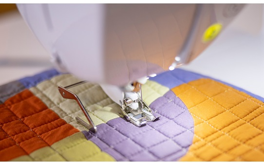 Close-up of the Brother Inventio NV1850Q stitching a colourful quilt