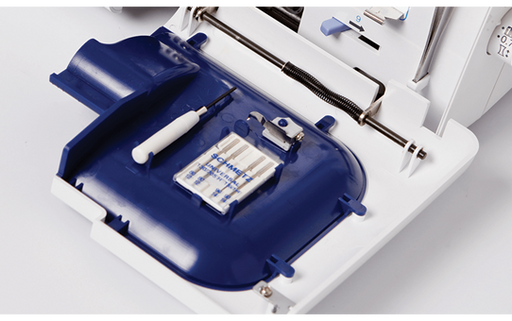 Open accessory compartment of the Brother 4234D overlocker showing needle set and accessories