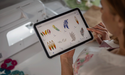 Selecting embroidery designs on a tablet beside the Brother Expedition BX1e
