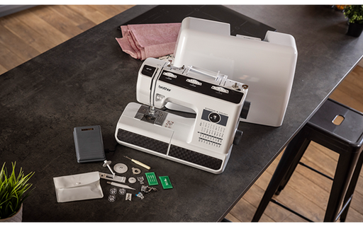 Brother HF37 heavy duty sewing machine with hard case open and accessories laid out on a dark table