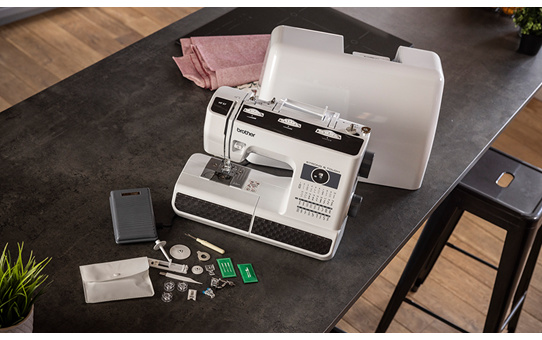 Brother HF37 heavy duty sewing machine with hard case open and accessories laid out on a dark table
